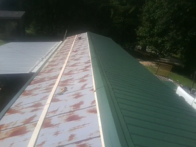 Old rusted panels beside newly installed green metal roofing — Wind Damage Roof Repair by Roofing Brothers in Wrentham