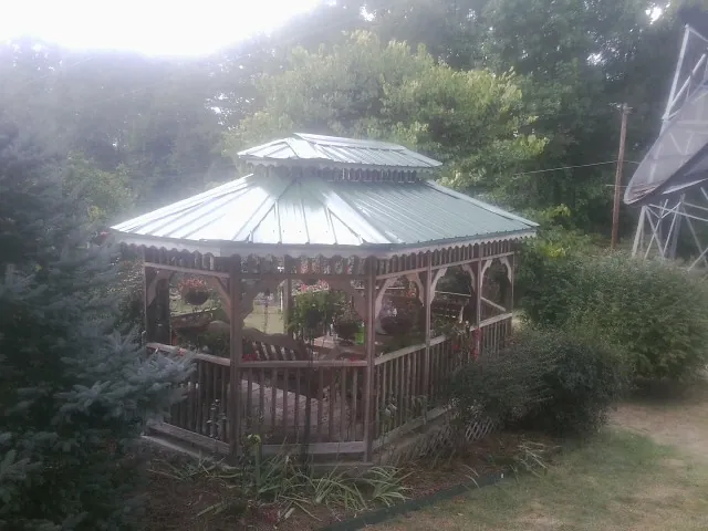 Green metal roof on a backyard gazebo surrounded by garden beds in Wrentham