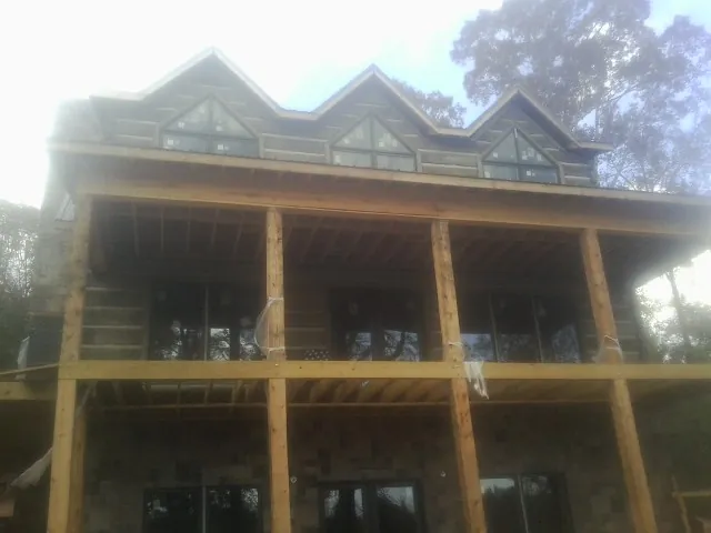 Dormers and porch framing on a large log home under construction — Roof Coating work by our crew in Wrentham