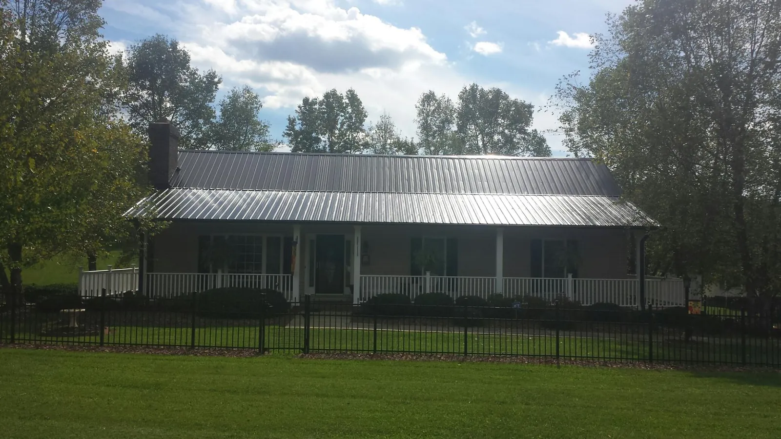 Gray metal roof on a brick ranch with a full width front porch — Gutter Guard Installation work by our crew in Wrentham